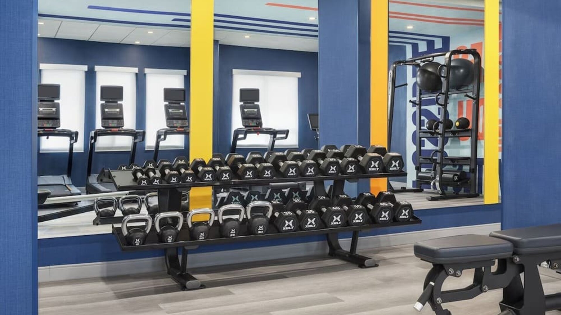 Fitness center with free weights, kettlebells, benches, and mirrored workout wall at Hampton Inn By Hilton Montreal East Anjou.