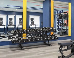 Fitness center with free weights, kettlebells, benches, and mirrored workout wall at Hampton Inn By Hilton Montreal East Anjou.