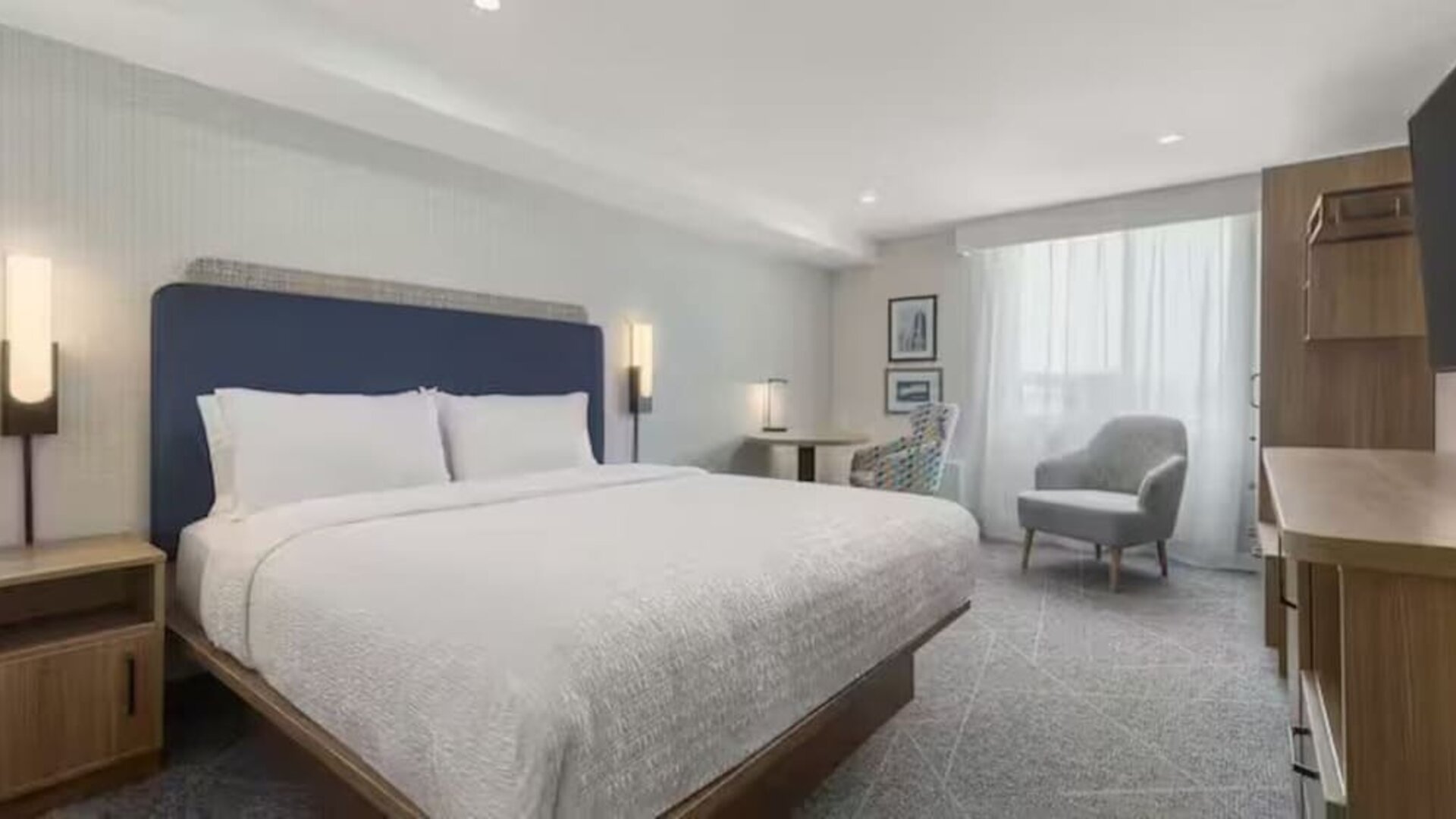 Spacious king guest room with seating area, work desk, large window, and contemporary furnishings at Hampton Inn By Hilton Montreal East Anjou.