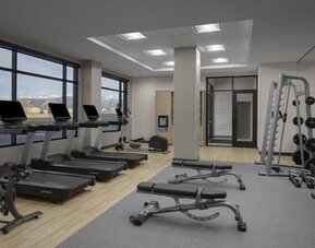 Fitness center with treadmills, free weights, benches, and strength training equipment at Hyatt Place Bozeman Yellowstone Airport.