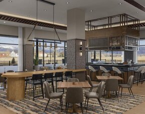 Modern dining area with communal tables, stylish bar seating, and floor-to-ceiling windows at Hyatt Place Bozeman Yellowstone Airport.