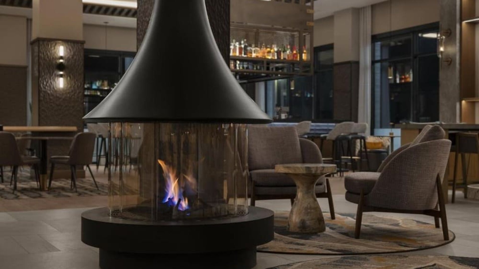 Modern lobby lounge featuring a suspended fireplace, comfortable seating, and inviting social spaces at Hyatt Place Bozeman Yellowstone Airport.