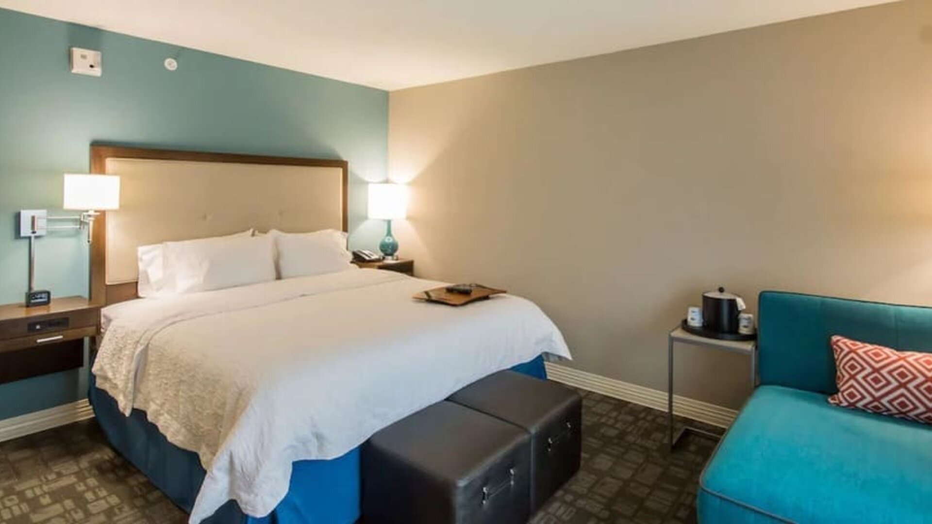 King guest room with comfortable bed, lounge chair, and contemporary décor at Hampton Inn & Suites Orlando at SeaWorld.