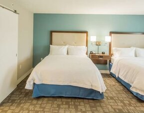 Guest room with two queen beds, spacious layout, and accessible bathroom entrance at Hampton Inn & Suites Orlando at SeaWorld.