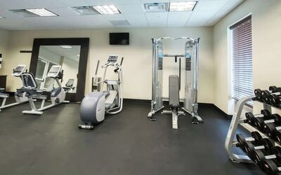 Fitness facility with strength training equipment, cardio machines, and dumbbell rack at Hampton Inn & Suites Orlando at SeaWorld.