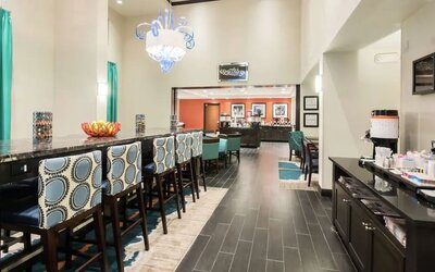 Hotel dining area with coffee station, communal seating, and breakfast service at Hampton Inn & Suites Orlando at SeaWorld.