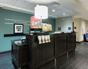 Front desk with guest services counter and modern lobby entrance at Hampton Inn & Suites Orlando at SeaWorld.