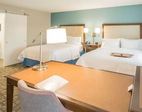 Guest room with two queen beds, work desk, and vanity area at Hampton Inn & Suites Orlando at SeaWorld.