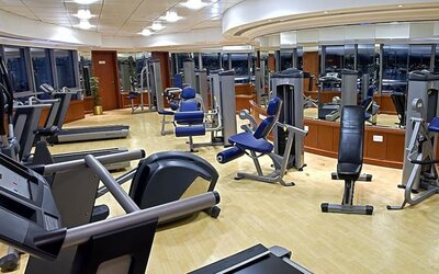 Modern fitness center with treadmills, cardio machines, weight equipment, mirrored walls, and spacious workout areas.