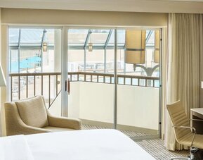 Spacious king room with plush bed, work desk, lounge chair, large window, and scenic outdoor view.