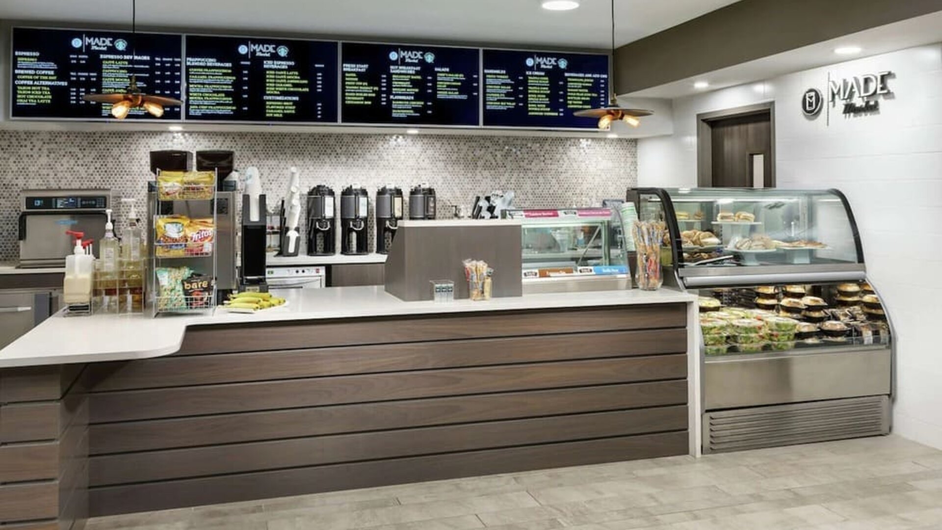 Fresh coffee station with menu boards, brewed coffee dispensers, grab-and-go snacks, and refrigerated food display.