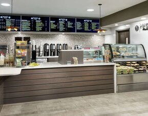 Fresh coffee station with menu boards, brewed coffee dispensers, grab-and-go snacks, and refrigerated food display.