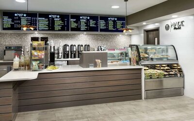 Fresh coffee station with menu boards, brewed coffee dispensers, grab-and-go snacks, and refrigerated food display.
