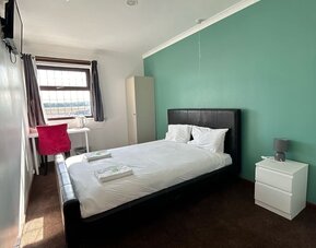 Bright guest room with double bed, work desk, wardrobe, and large window at Stay Inn Express.