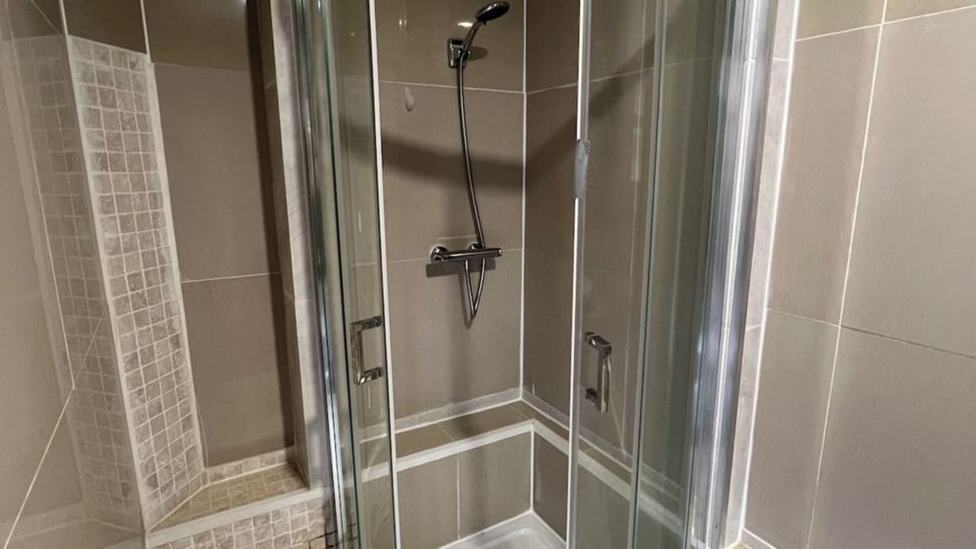 Glass-enclosed shower with modern fixtures and tiled walls at Stay Inn Express.