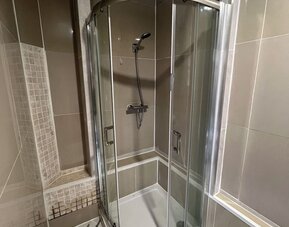 Glass-enclosed shower with modern fixtures and tiled walls at Stay Inn Express.