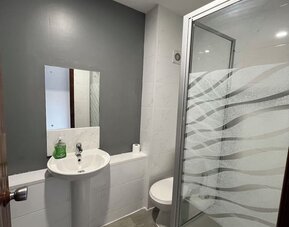 Bathroom with walk-in shower, pedestal sink, and modern finishes at Stay Inn Express.