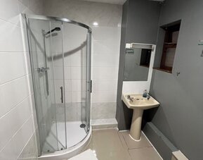 Bathroom with glass-enclosed shower, pedestal sink, and modern tiled design at Stay Inn Express.