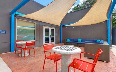 Outdoor patio with lounge seating, café tables, and shade sails at Tru By Hilton Lithia Springs.Modern reception area with front desk services and guest check-in at Tru By Hilton Lithia Springs.