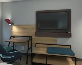 Guest room workspace with desk, lounge seating, flat-screen TV, and modern furnishings at Tru By Hilton Lithia Springs.