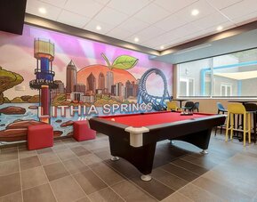 Game room with pool table, colorful Lithia Springs mural, and casual lounge seating at Tru By Hilton Lithia Springs.