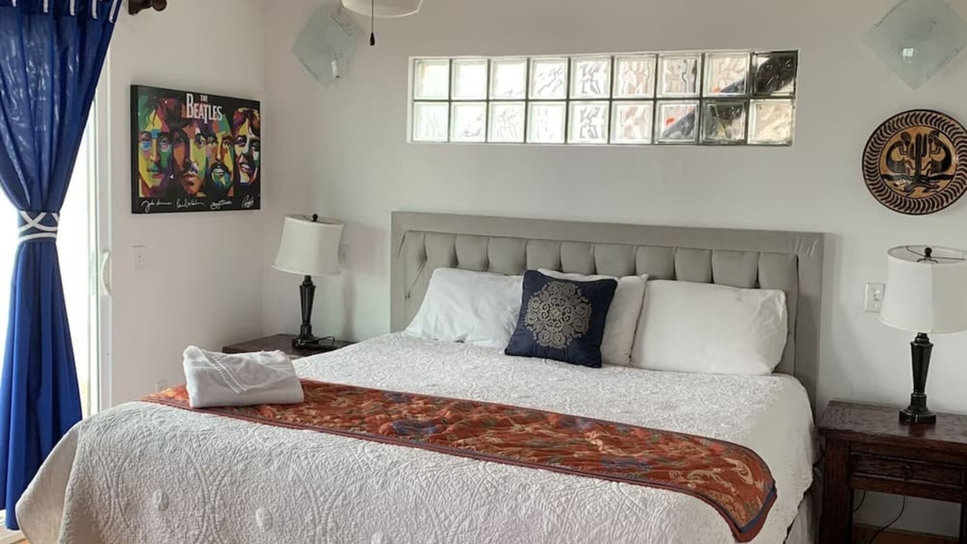Bright king bedroom with elegant furnishings, exposed wooden beams, and adjoining lounge area at Casa Playa Baja Resort.