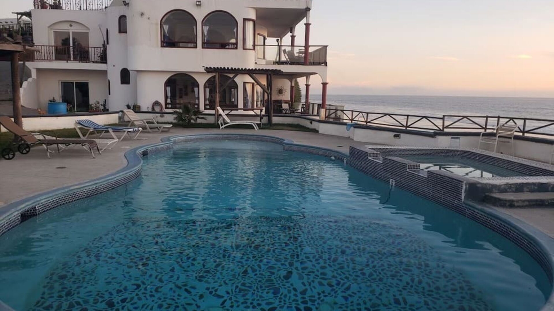 Oceanfront swimming pool with hot tub, sun loungers, and sunset views at Casa Playa Baja Resort.