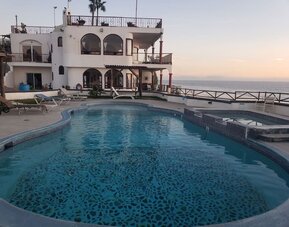 Oceanfront swimming pool with hot tub, sun loungers, and sunset views at Casa Playa Baja Resort.