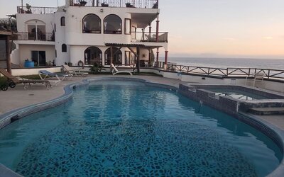 Oceanfront swimming pool with hot tub, sun loungers, and sunset views at Casa Playa Baja Resort.