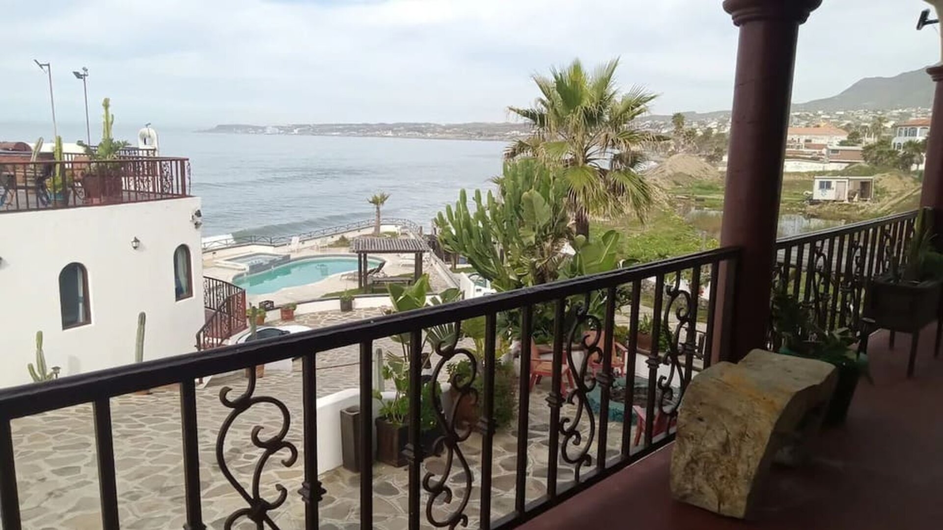 Private balcony overlooking the ocean, pool, and landscaped resort grounds at Casa Playa Baja Resort.