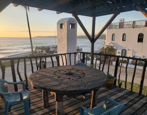 Oceanfront balcony with rustic seating area and panoramic sunset views at Casa Playa Baja Resort.