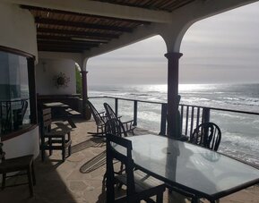 Covered beachfront terrace with outdoor dining and unobstructed ocean views at Casa Playa Baja Resort.