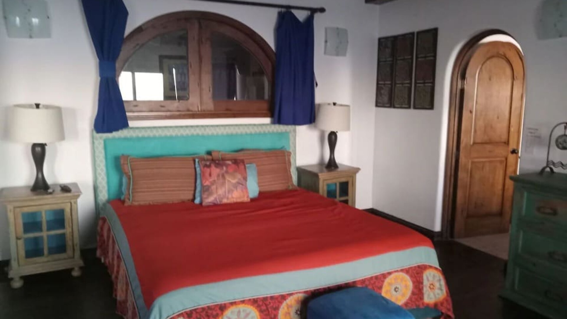 Spacious bedroom with king-size bed, rustic wood accents, exposed beams, and colorful décor at Casa Playa Baja Resort.