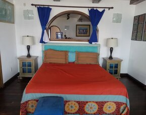 Colorful king bedroom with rustic furnishings, exposed beams, and traditional Mexican-inspired décor at Casa Playa Baja Resort.