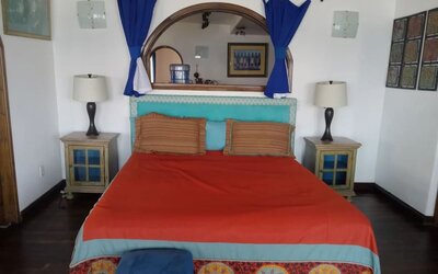 Colorful king bedroom with rustic furnishings, exposed beams, and traditional Mexican-inspired décor at Casa Playa Baja Resort.