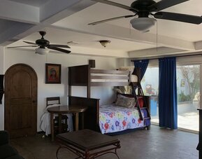 Family suite with bunk beds, lounge area, and direct access to the outdoor patio at Casa Playa Baja Resort.