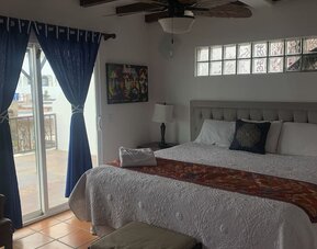 King bedroom with private balcony access, tiled floors, and comfortable seating at Casa Playa Baja Resort.