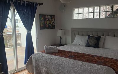King bedroom with private balcony access, tiled floors, and comfortable seating at Casa Playa Baja Resort.