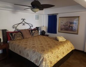 Comfortable guest bedroom with king-size bed, traditional furnishings, and warm rustic accents at Casa Playa Baja Resort.