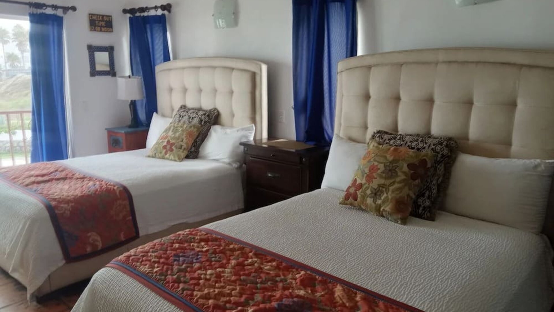 Double queen guest room with balcony access, natural light, and spacious accommodations at Casa Playa Baja Resort.
