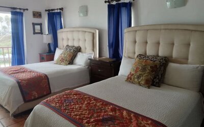 Double queen guest room with balcony access, natural light, and spacious accommodations at Casa Playa Baja Resort.