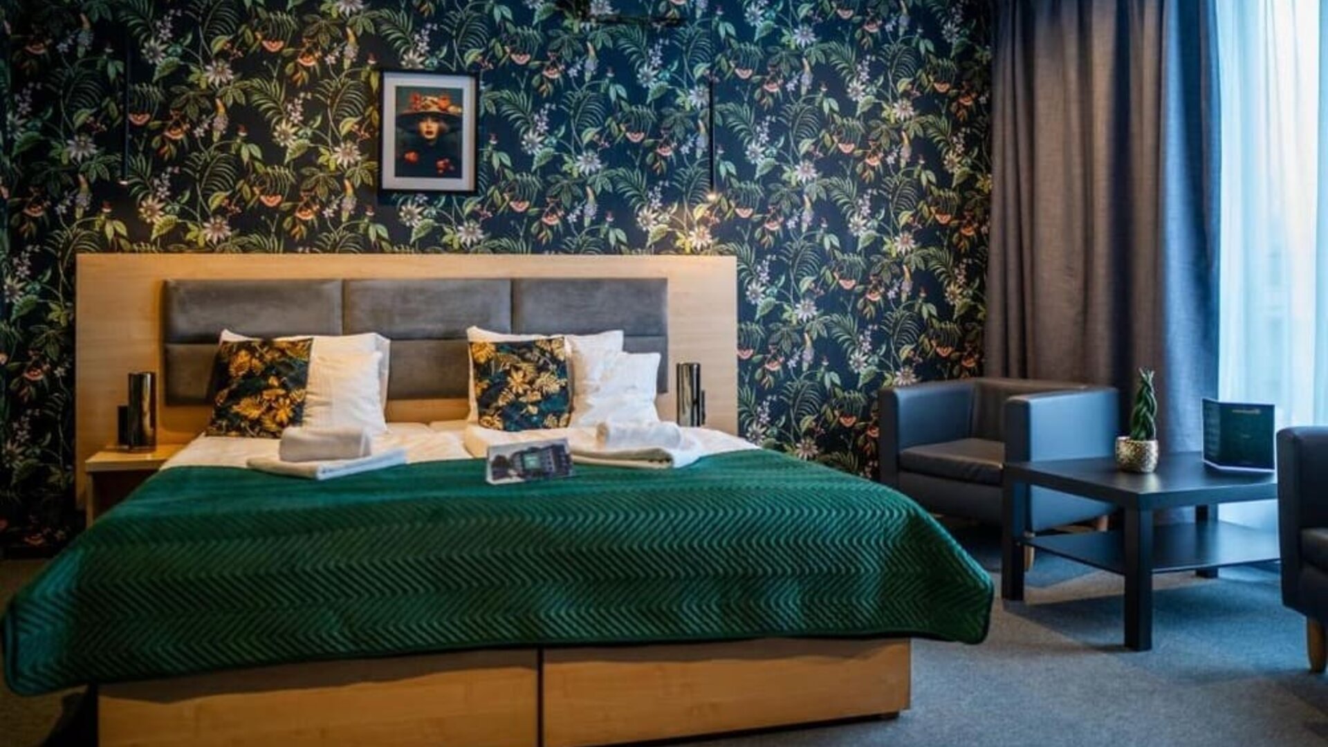 Spacious king guest room with botanical feature wall and seating area at Hotel Seven.