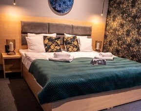 Contemporary king guest room with feature lighting and botanical wallpaper at Hotel Seven.