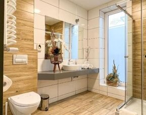 Modern hotel bathroom with walk-in glass shower, floating vanity and wood-effect tiles at Hotel Seven.