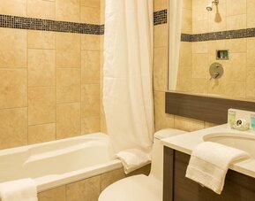 Contemporary guest bathroom featuring a bathtub, vanity and modern tiled finishes at Le Chabrol Hotel Et Suites.
