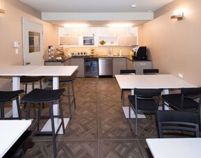 Bright breakfast room with communal seating and self-service refreshments at Le Chabrol Hotel Et Suites.