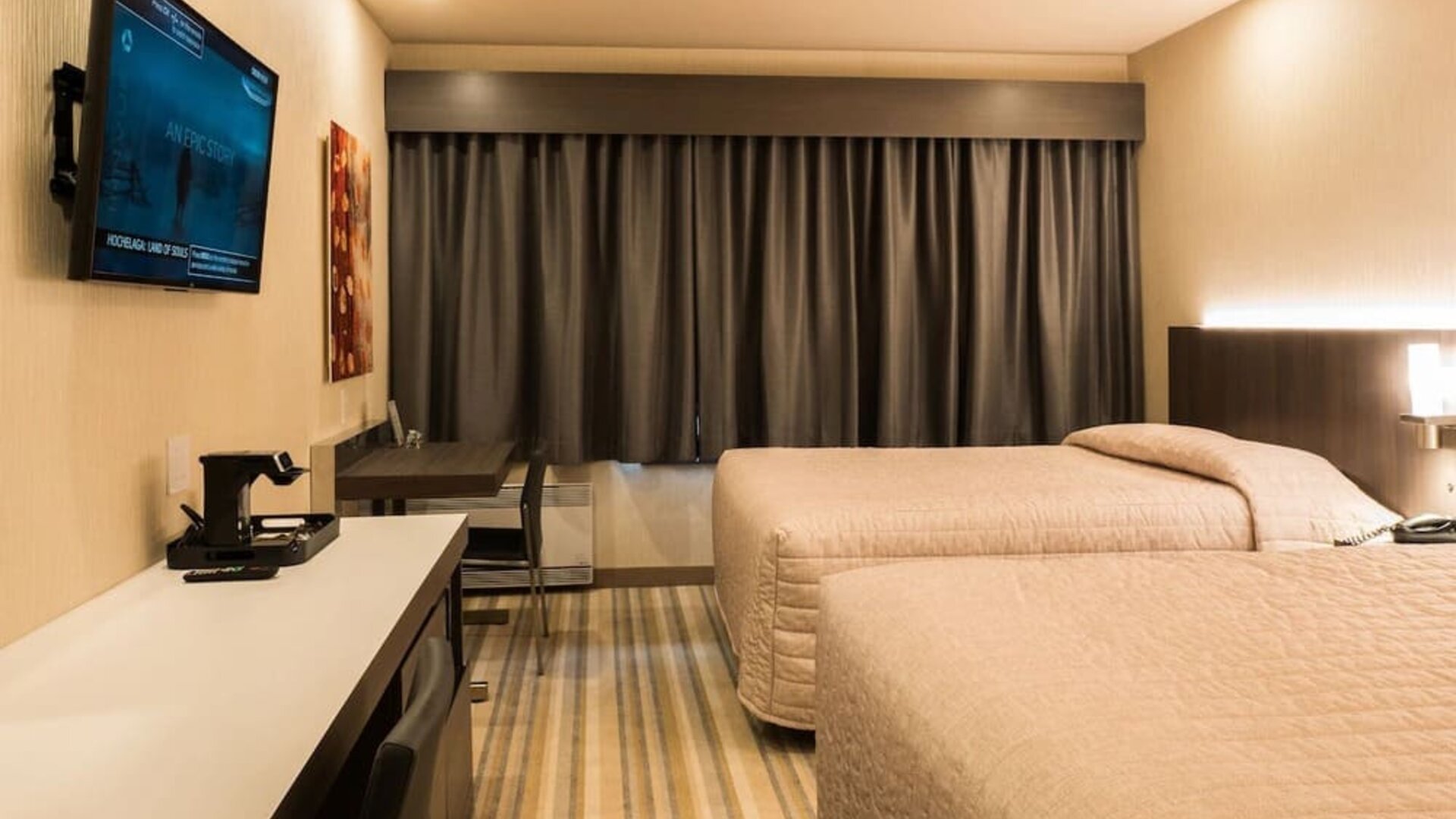 Comfortable twin guest room with workspace and modern amenities at Le Chabrol Hotel Et Suites.