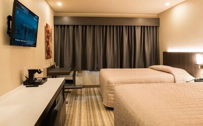 Comfortable twin guest room with workspace and modern amenities at Le Chabrol Hotel Et Suites.