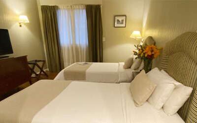 Twin guest room offering two comfortable beds, warm lighting, classic furnishings, and a relaxing atmosphere for families or friends traveling together at Hotel Lafayette.
