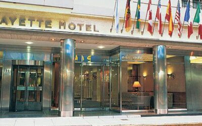 Exterior entrance of the hotel featuring an international flag display, modern glass frontage, and a prime central location at Hotel Lafayette.